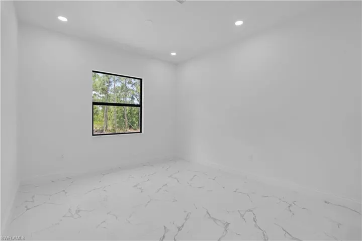 Empty room featuring marble look tiles and recessed lighting