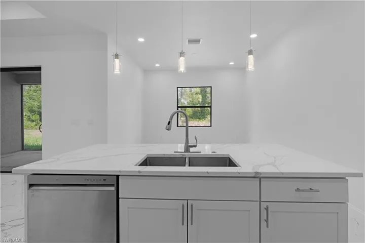 Kitchen featuring stainless steel dishwasher, light stone counters, decorative light fixtures, recessed lighting, and open floor plan