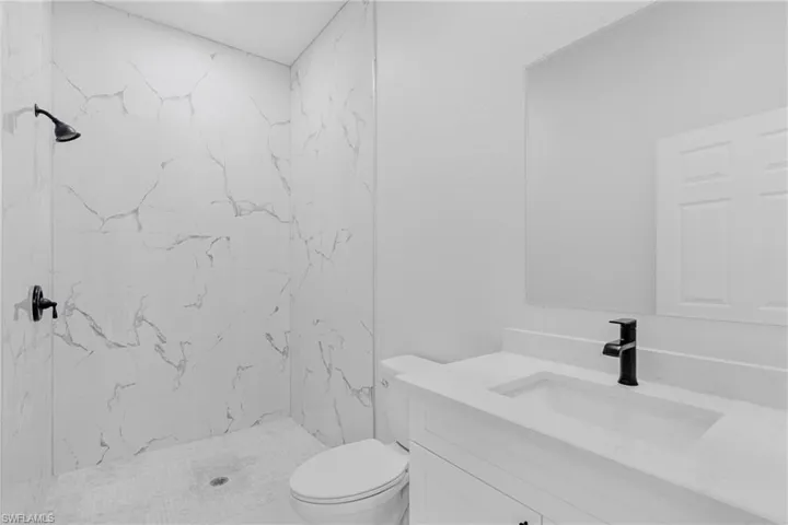 Bathroom featuring vanity and a marble finish shower