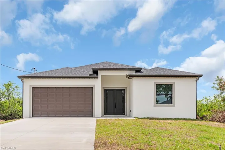 Prairie-style home featuring stucco siding, an attached garage, driveway, a front yard, and a shingled roof
