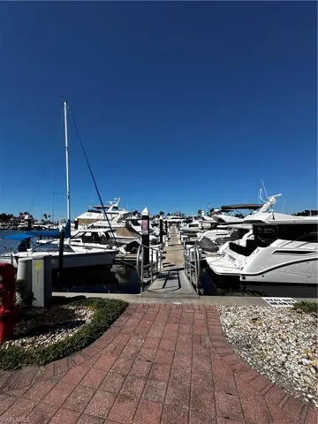 Marina with multiple docked vessels, featuring a red paver walkway, manicured landscaping, and a secure gangway