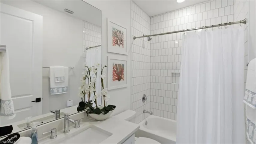 Bathroom with vanity and shower / bathtub combination with curtain - Virtually Edited