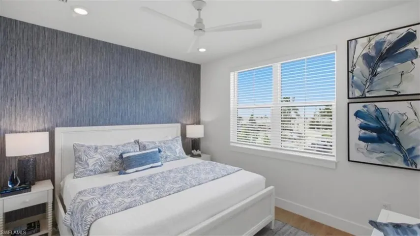 Bedroom featuring an accent wall, ceiling fan, wood finished floors, wallpapered walls, and recessed lighting - Virtually Edited