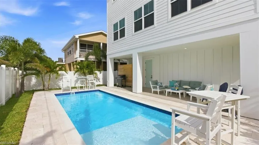 View of pool with a balcony, an outdoor lounge area, a fenced backyard, patio surround, and a grill - Virtually Edited
