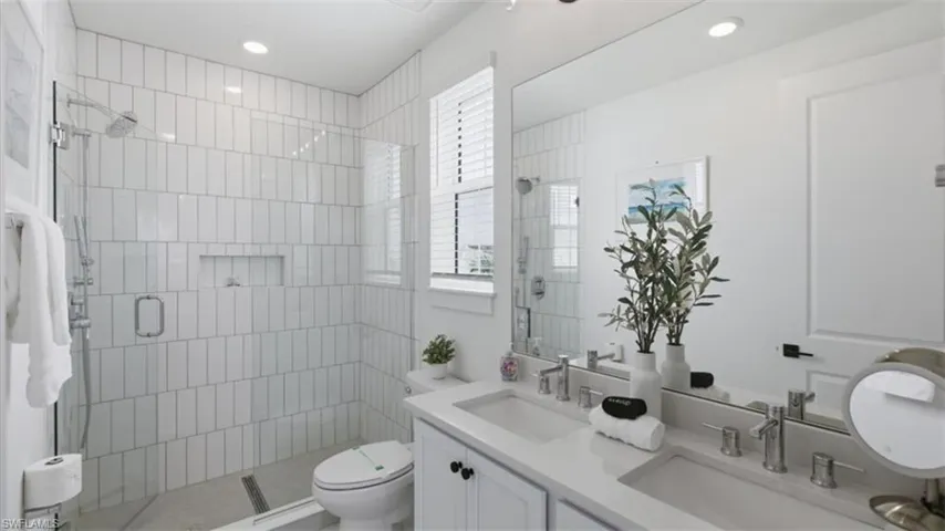 Full bath with double vanity, a stall shower, and recessed lighting - Virtually Edited