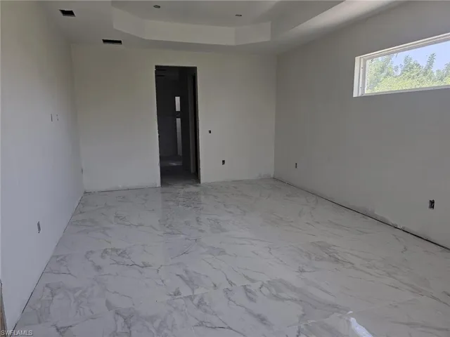 Spare room featuring a raised ceiling and light tile floors