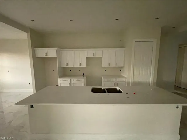 Kitchen with sink, white cabinets, light tile patterned floors, and a center island