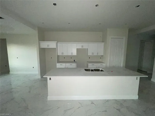 Kitchen with a large island, white cabinets, and sink