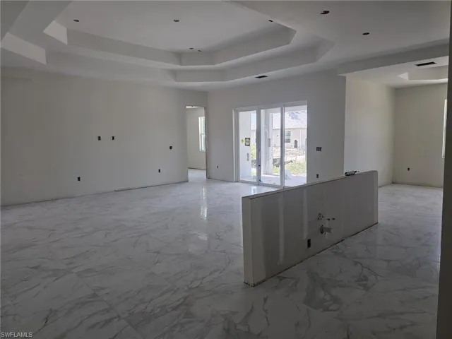 Unfurnished room featuring a raised ceiling and light tile flooring