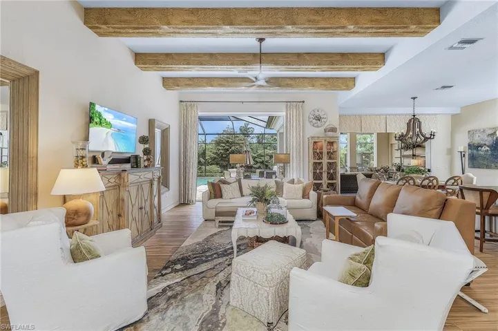 Living room featuring hardwood / wood-style floors, beam ceiling, and ceiling fan with notable chandelier