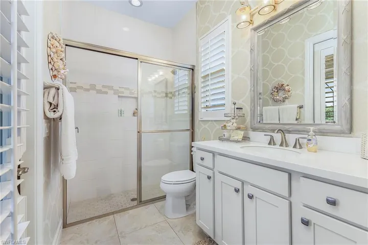 Bathroom with a shower with door, tile flooring, toilet, and vanity