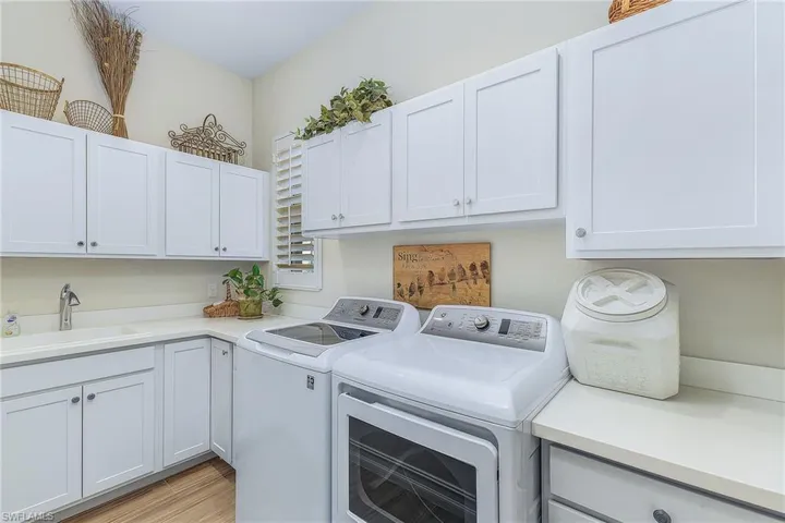 Laundry area featuring cabinets, sink, washing machine and dryer, and light wood-type flooring