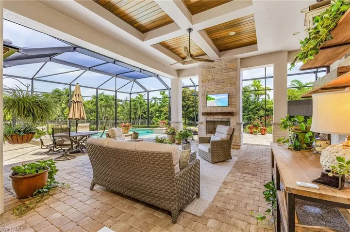 Sunroom featuring coffered ceiling, ceiling fan, wooden ceiling, beamed ceiling, and an outdoor stone fireplace