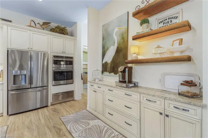 Kitchen with light hardwood / wood-style floors, light stone countertops, and stainless steel appliances