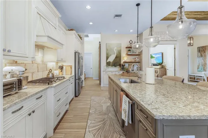 Kitchen featuring an island with sink, white cabinetry, sink, and tasteful backsplash