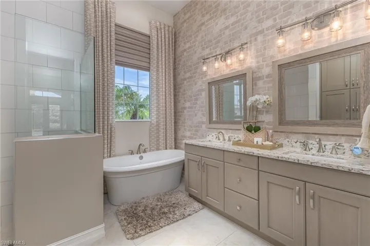 Bathroom featuring tile floors, a bathing tub, double vanity, and tile walls