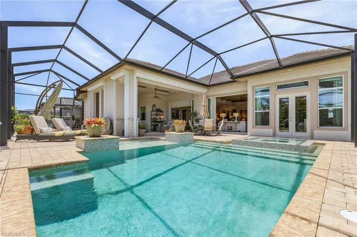 View of swimming pool featuring ceiling fan, glass enclosure, and a patio area