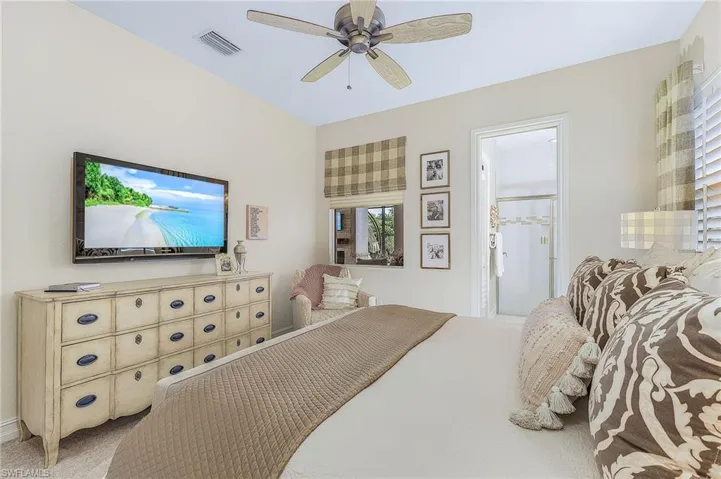 Carpeted bedroom featuring ceiling fan and ensuite bath