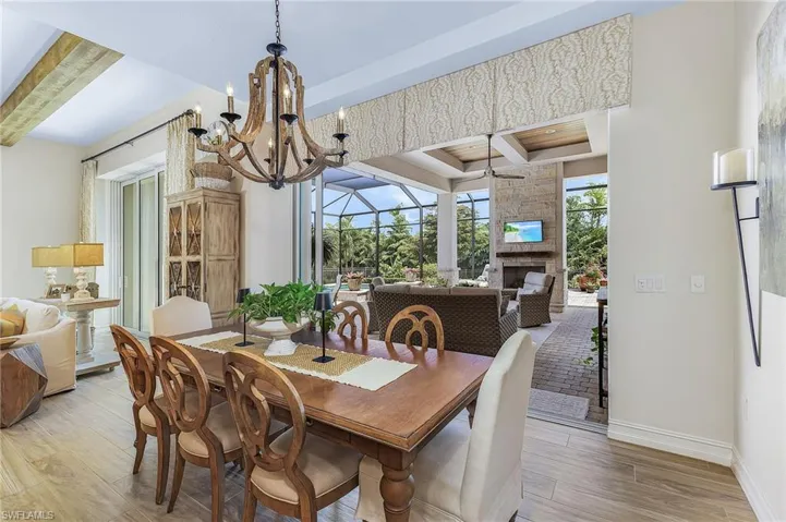 Dining area featuring a fireplace, a tray ceiling, beam ceiling, wood-type flooring, and a chandelier