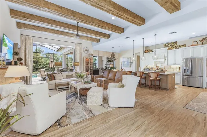Living room with a notable chandelier, beam ceiling, and light wood-type flooring