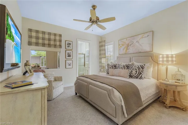 Carpeted bedroom featuring ceiling fan and ensuite bathroom