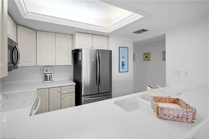 Kitchen featuring visible vents, a sink, freestanding refrigerator, black microwave, and light countertops