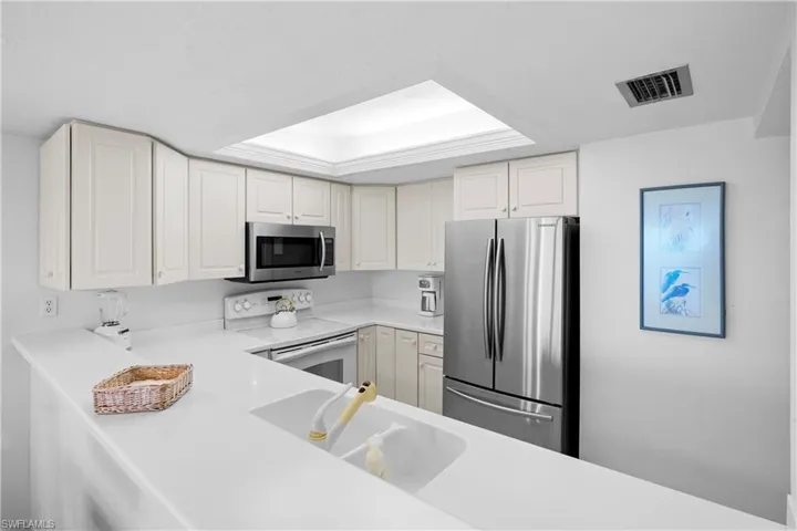 Kitchen with visible vents, a sink, light countertops, white cabinets, and appliances with stainless steel finishes