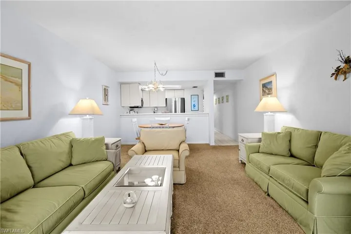 Living area with a chandelier, visible vents, and light colored carpet