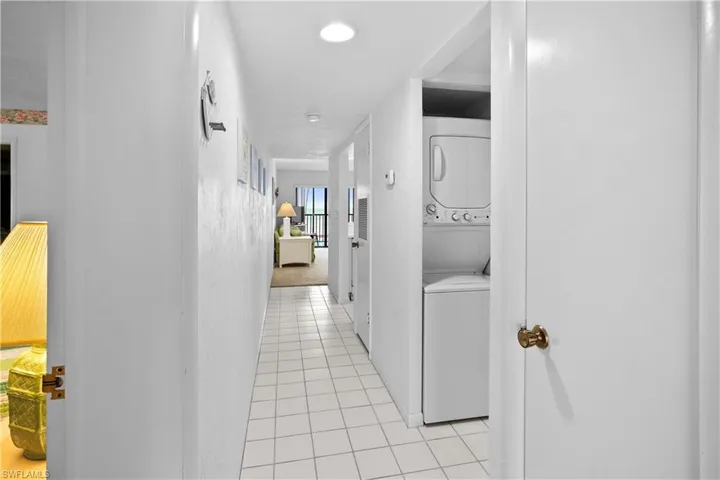 Hall with light tile patterned floors and stacked washer and clothes dryer
