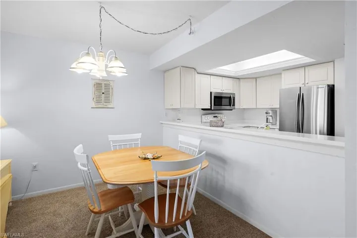 Carpeted dining room with baseboards and an inviting chandelier