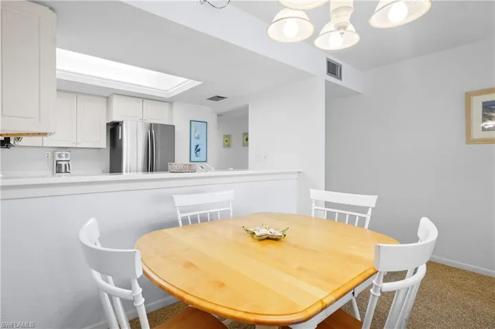 Carpeted dining room with a raised ceiling, baseboards, and visible vents