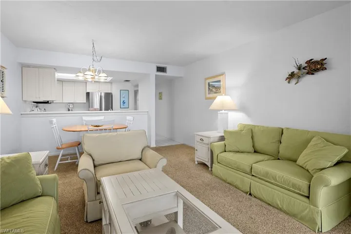 Living area featuring visible vents, carpet floors, and a chandelier