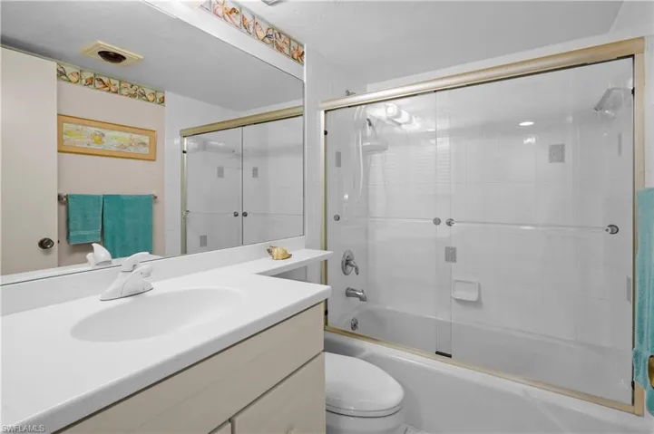Bathroom featuring combined bath / shower with glass door, toilet, vanity, and visible vents
