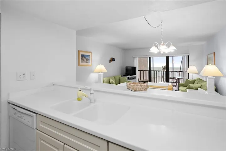 Kitchen with a sink, dishwasher, open floor plan, and an inviting chandelier