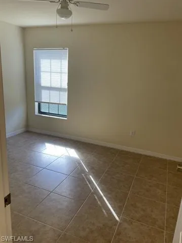 Empty room with light tile patterned floors and a ceiling fan