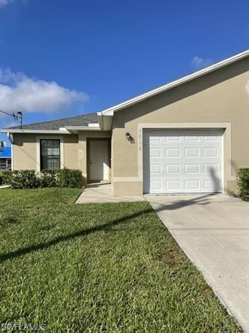 Ranch-style home featuring stucco siding, a front lawn, driveway, and roof with shingles