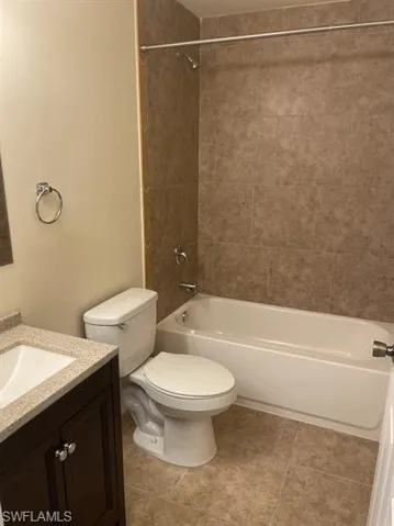 Bathroom featuring vanity, shower / bath combination, and light tile patterned flooring