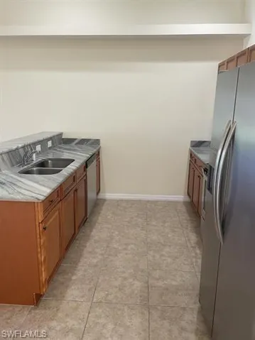 Kitchen with brown cabinets, appliances with stainless steel finishes, and light stone countertops