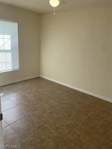 Spare room featuring baseboards and dark tile patterned flooring