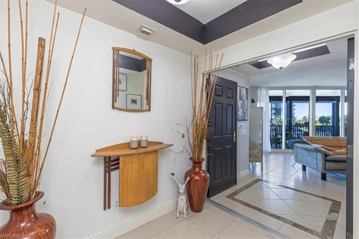 Entryway foyer with inlaid tile floor details and double doors into the residence