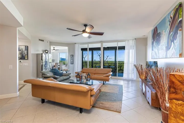 Living area with open floorplan featuring expansive windows, tile floors, and ceiling fan
