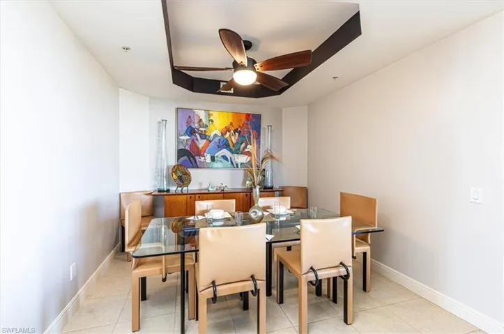 Dining room featuring a tray ceiling, a ceiling fan, and tile floors