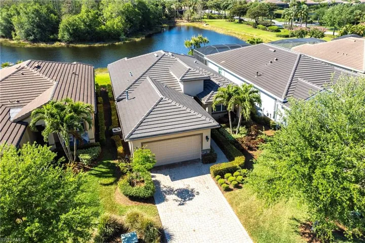 Waterfront property featuring a paver driveway, an attached garage, and mature landscaping