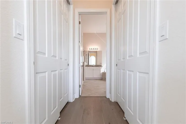 Hallway with wood-finish flooring, flanked by two panel-style bi-fold closet doors