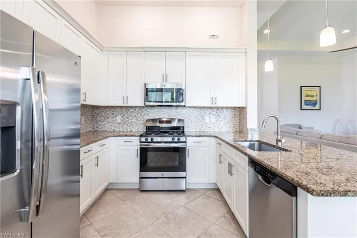 U-shaped kitchen featuring white cabinetry and granite countertops