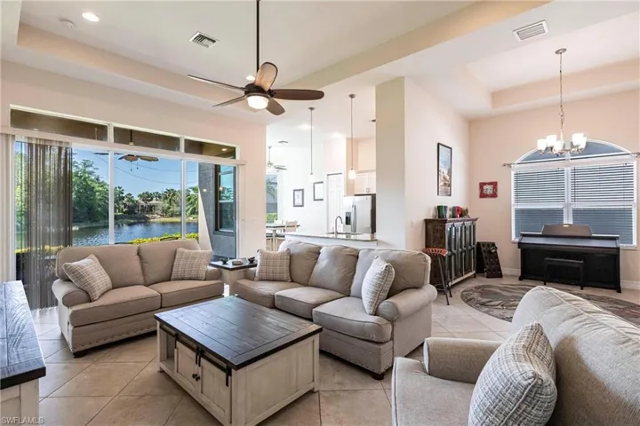 Spacious living area featuring large format tile flooring and a tray ceiling with recessed lighting