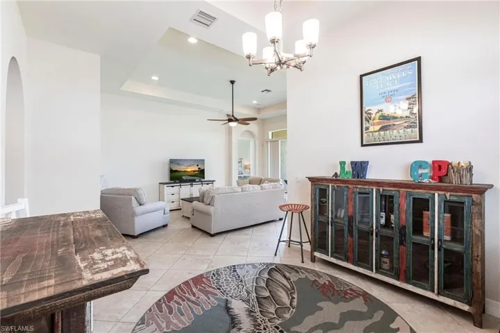 Spacious living area featuring tile flooring, an arched entryway, recessed lighting, and a tray ceiling