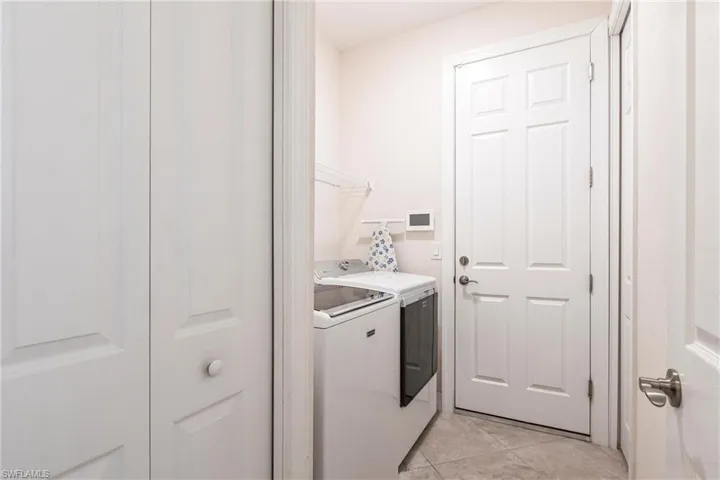 Dedicated laundry area featuring tile flooring and a paneled door