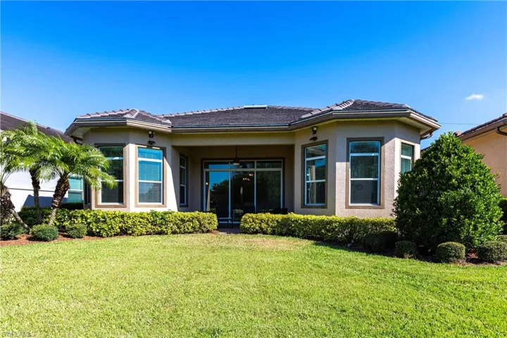 Expansive rear lawn featuring mature landscaping and a covered patio with sliding glass doors