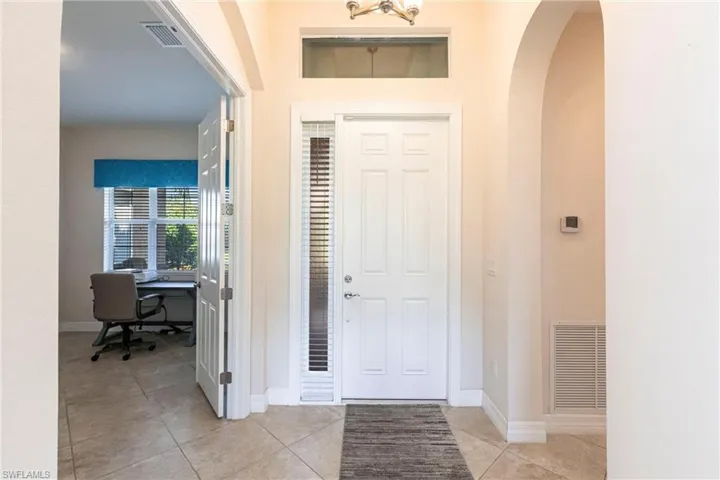 Entryway featuring a paneled door with a sidelight, transom window, and tiled flooring